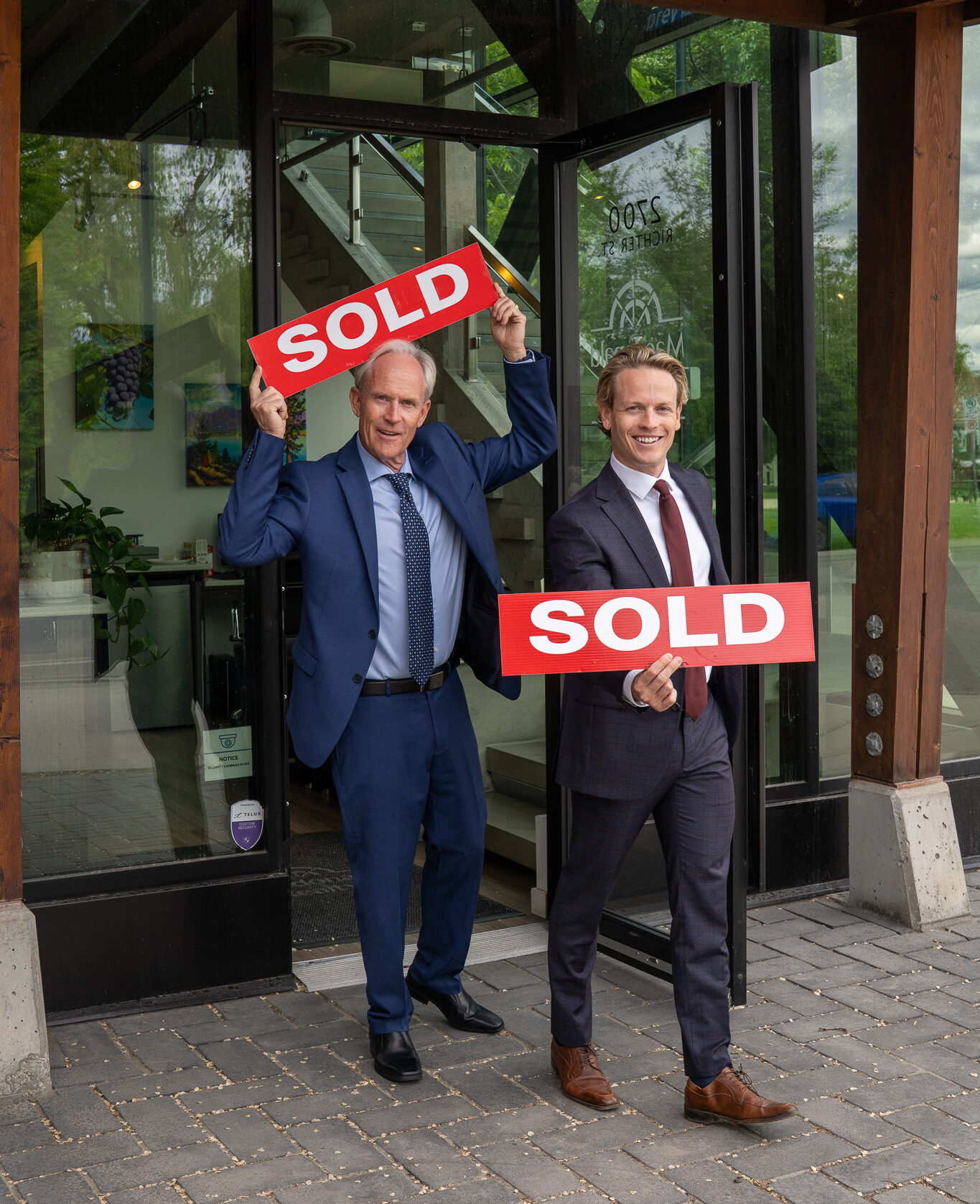 Okanagan Realtors David Jurome and Jaxon Jurome of Macdonald Realty Kelowna holding sold signs and selling properties in british columbia