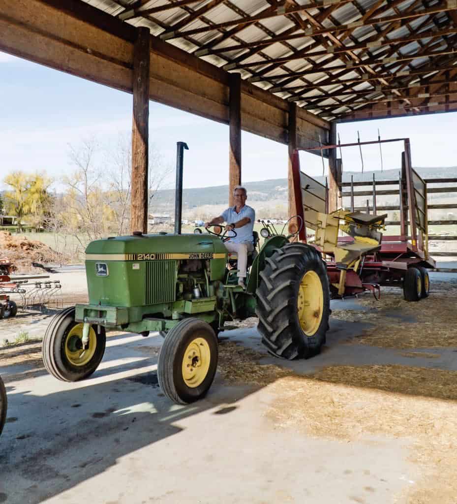 Kelowna Realtor David Jurome riding a tractor and selling a farm property in the Okanagan Valley